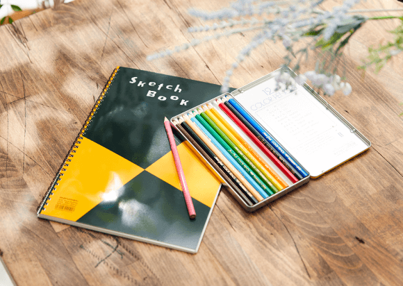 机の上に置かれた趣味のスケッチブックと色鉛筆